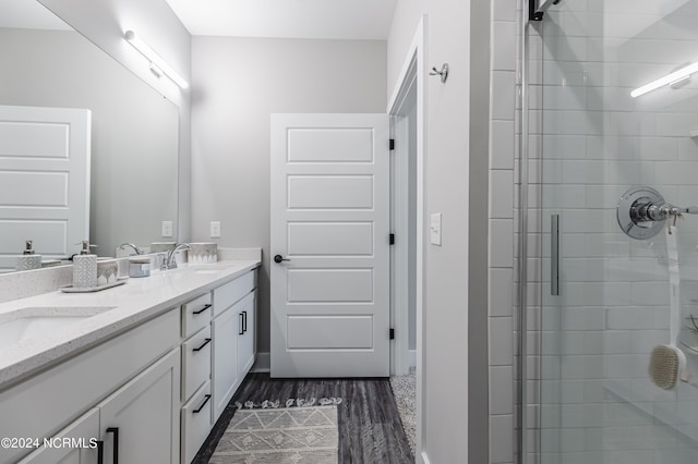 bathroom with a shower with shower door, hardwood / wood-style floors, and vanity