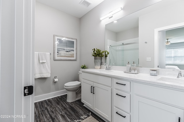 bathroom with an enclosed shower, toilet, wood-type flooring, ceiling fan, and vanity