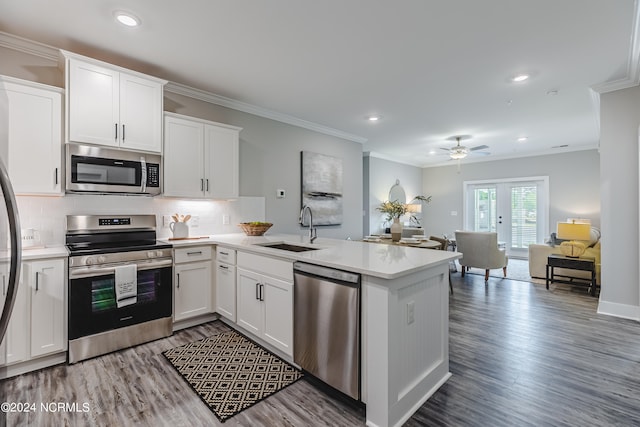 kitchen featuring stainless steel appliances, sink, kitchen peninsula, and white cabinets