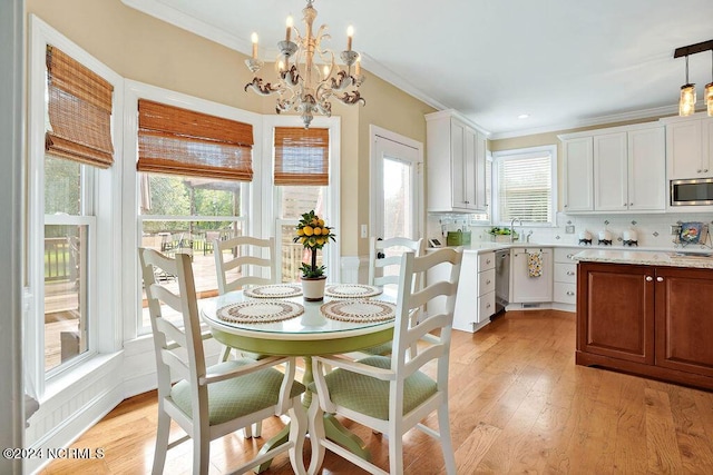 dining room with a wealth of natural light, crown molding, a chandelier, and light hardwood / wood-style floors