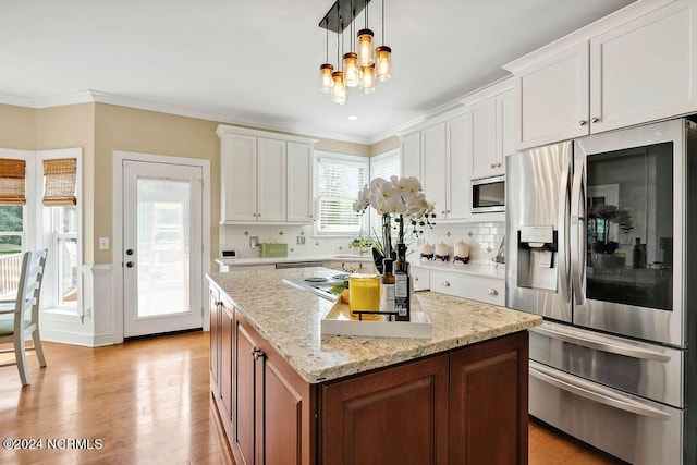 kitchen featuring a center island, white cabinets, stainless steel appliances, and decorative light fixtures