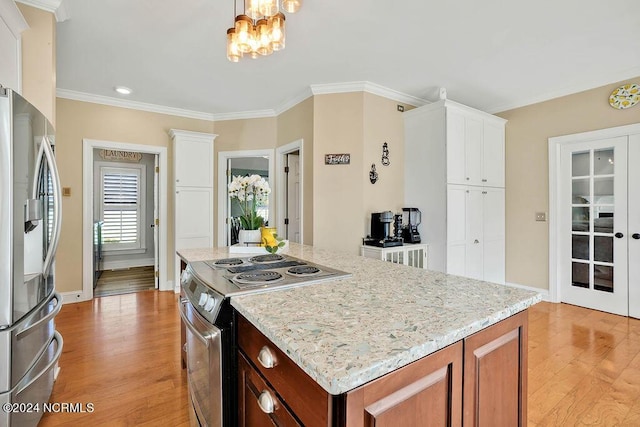 kitchen with white cabinets, a kitchen island, ornamental molding, and appliances with stainless steel finishes