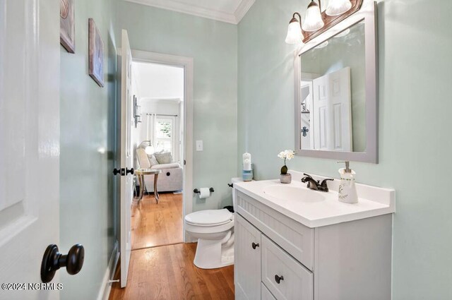 clothes washing area with cabinets, washing machine and dryer, crown molding, and hardwood / wood-style flooring