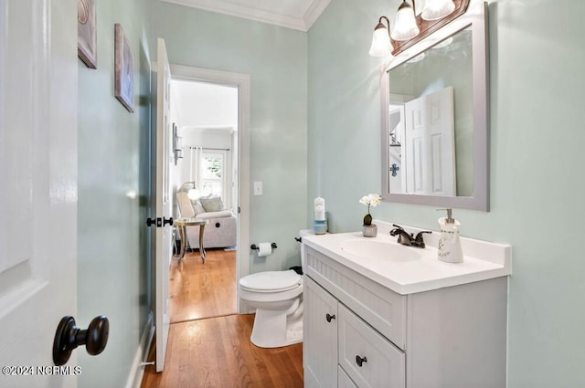 bathroom featuring crown molding, vanity, wood-type flooring, and toilet