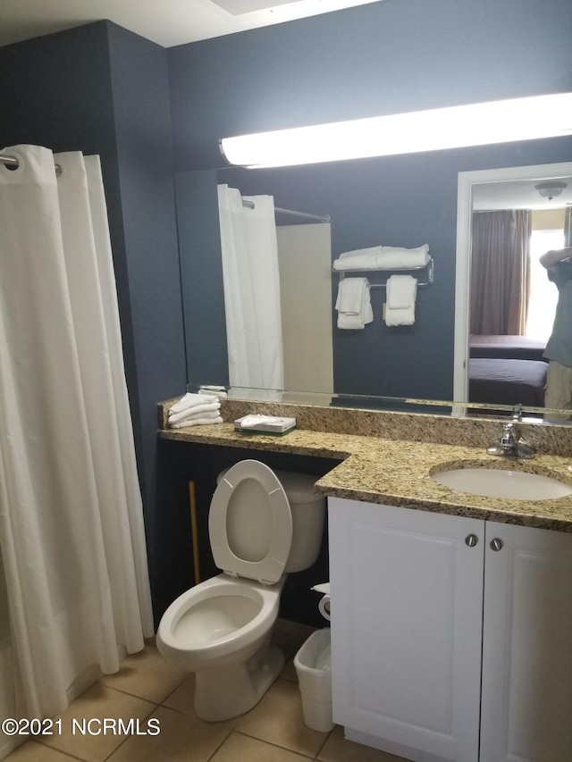 bathroom featuring tile patterned floors, toilet, walk in shower, and vanity