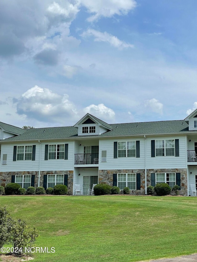 multi unit property with a balcony and a front yard