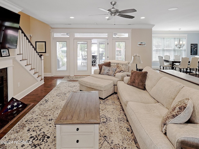 living room featuring ceiling fan with notable chandelier, ornamental molding, and dark hardwood / wood-style flooring