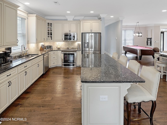 kitchen with pendant lighting, pool table, sink, stainless steel appliances, and dark hardwood / wood-style flooring