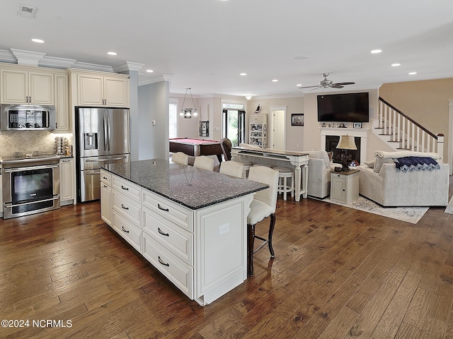 kitchen featuring a breakfast bar, pool table, a center island, dark hardwood / wood-style floors, and stainless steel appliances