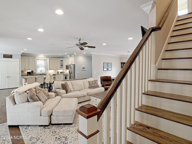 living room with ceiling fan, light wood-type flooring, and ornamental molding