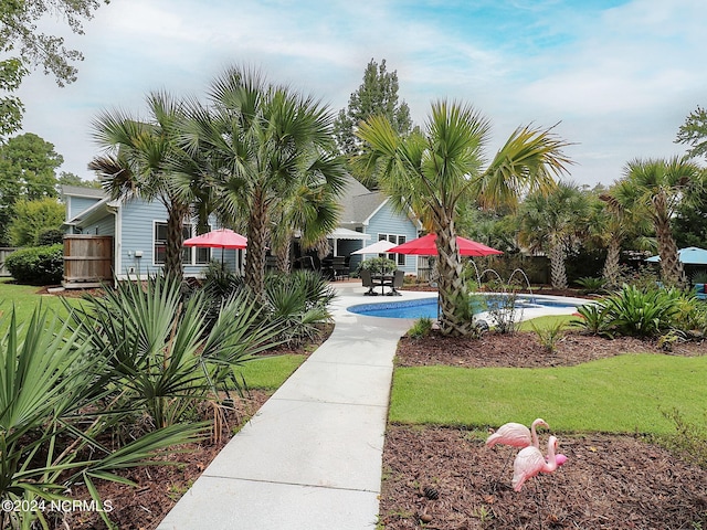 view of property's community with a pool, a patio area, and a yard