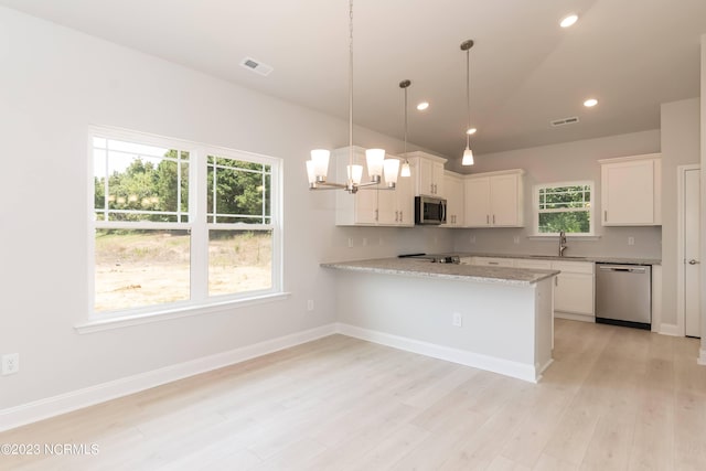 kitchen featuring appliances with stainless steel finishes, light hardwood / wood-style flooring, light stone countertops, white cabinetry, and kitchen peninsula