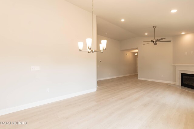 unfurnished living room with light hardwood / wood-style flooring, lofted ceiling, ceiling fan with notable chandelier, and a premium fireplace