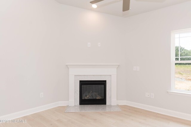 interior space with ceiling fan, a fireplace, and light hardwood / wood-style flooring