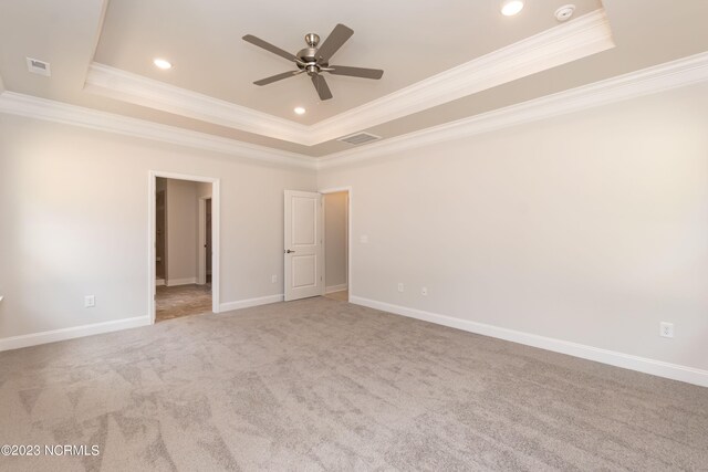 carpeted spare room with ceiling fan, crown molding, and a tray ceiling