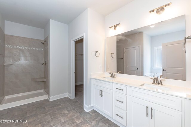 bathroom featuring tile patterned flooring, a tile shower, and vanity