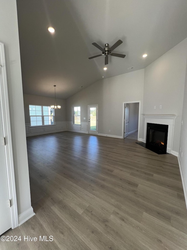 unfurnished living room featuring ceiling fan with notable chandelier, lofted ceiling, and dark wood-type flooring