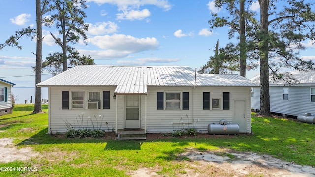 view of front of home with entry steps, metal roof, and a front yard