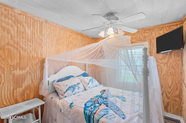 bedroom featuring ceiling fan and wooden walls