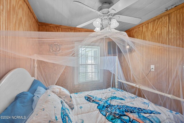 bedroom with vaulted ceiling, wood walls, and ceiling fan