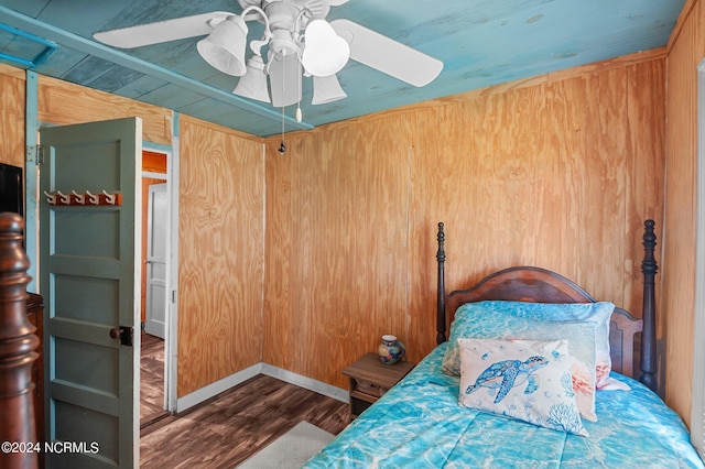 bedroom featuring ceiling fan, wood walls, and wood-type flooring