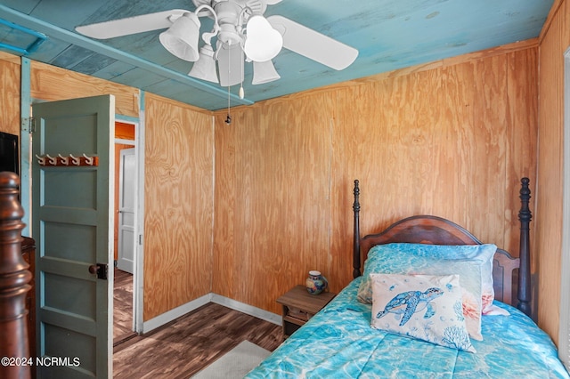 bedroom featuring a ceiling fan, wood walls, and wood finished floors