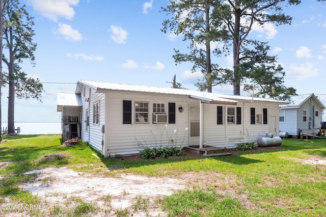 view of front facade featuring cooling unit, metal roof, and a front lawn