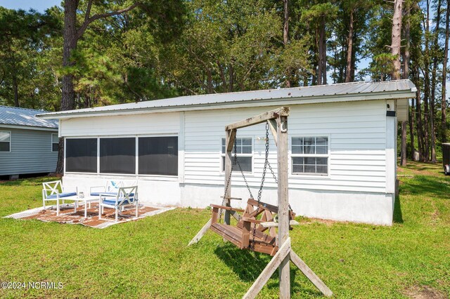 back of house featuring metal roof and a lawn