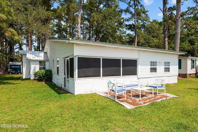 back of house featuring metal roof, a patio area, and a yard