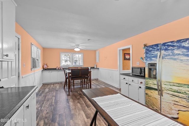 dining area featuring a wainscoted wall, ceiling fan, and dark wood finished floors