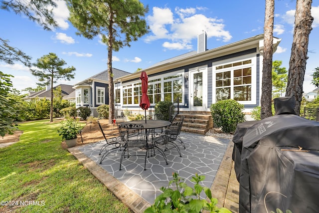 rear view of house with a patio, a chimney, a lawn, entry steps, and outdoor dining space