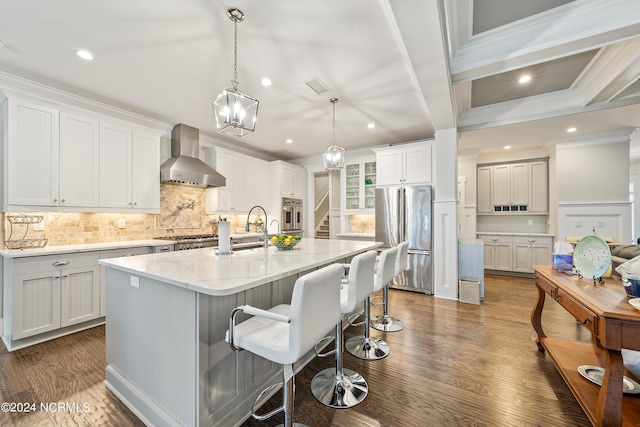 kitchen featuring stainless steel appliances, a spacious island, white cabinetry, a sink, and wall chimney exhaust hood