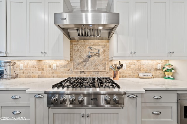 kitchen featuring light stone counters, range hood, white cabinets, and stainless steel gas stovetop