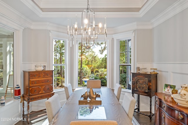 dining space featuring a notable chandelier, a tray ceiling, crown molding, and a decorative wall