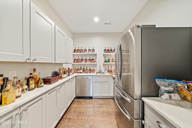 kitchen with white cabinets, appliances with stainless steel finishes, open shelves, and light countertops