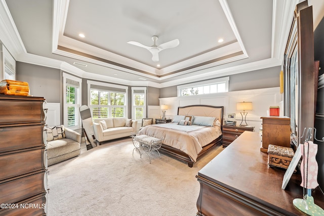 carpeted bedroom featuring a wainscoted wall, a raised ceiling, crown molding, and a decorative wall