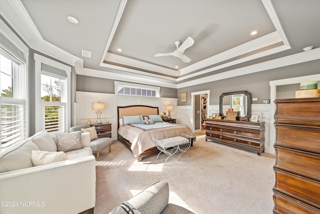 bedroom featuring light colored carpet, a raised ceiling, wainscoting, and visible vents