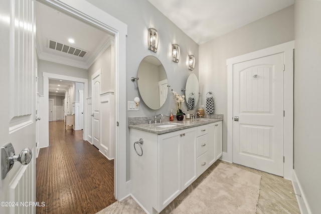 bathroom featuring double vanity, visible vents, a sink, and wood finished floors