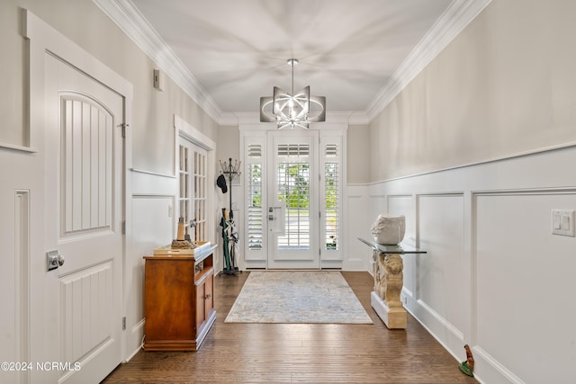 foyer with dark wood-style floors, ornamental molding, an inviting chandelier, and a decorative wall