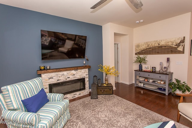 living room featuring ceiling fan, a stone fireplace, and wood-type flooring