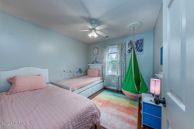 bedroom featuring ceiling fan, hardwood / wood-style floors, and a textured ceiling