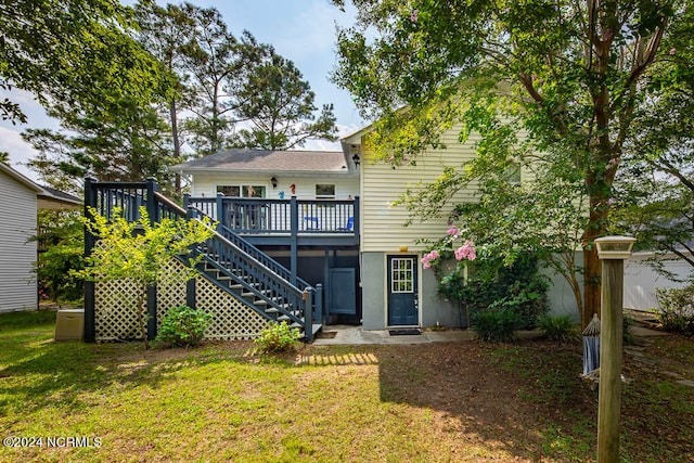 back of property featuring a lawn and a wooden deck