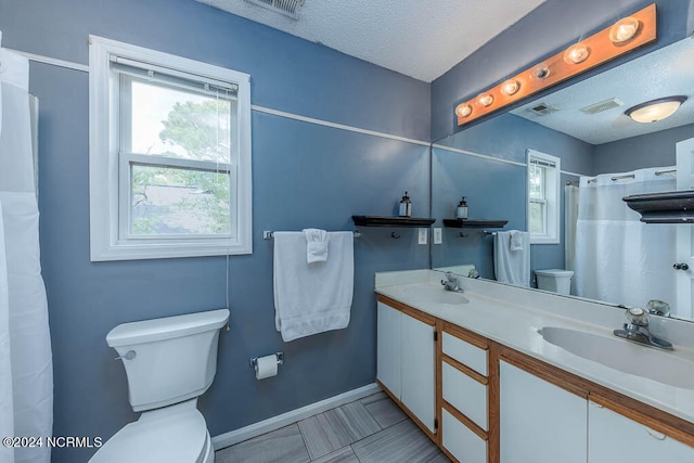 bathroom featuring tile patterned flooring, a textured ceiling, walk in shower, vanity, and toilet