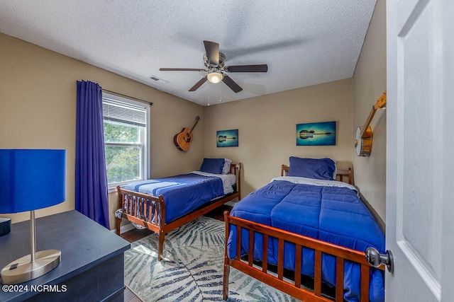 bedroom with a textured ceiling, wood-type flooring, and ceiling fan