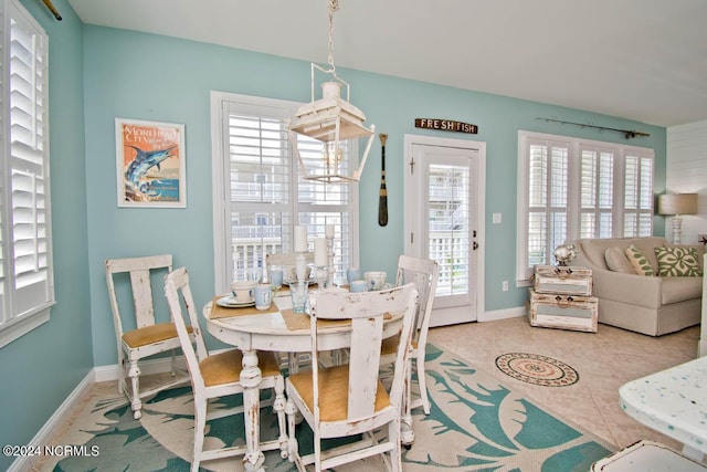 tiled dining space featuring baseboards and a healthy amount of sunlight