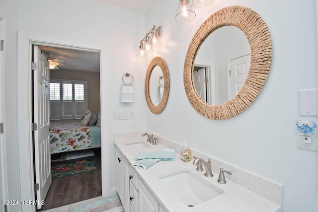 ensuite bathroom featuring double vanity, connected bathroom, a sink, and wood finished floors