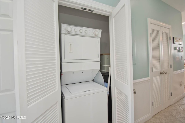 washroom featuring light tile patterned floors and stacked washing maching and dryer