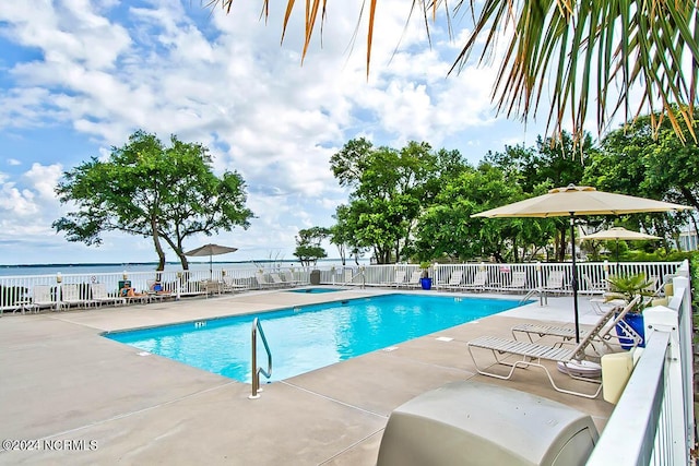 view of pool featuring a water view and a patio