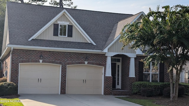 view of front of property featuring a shingled roof, brick siding, and driveway