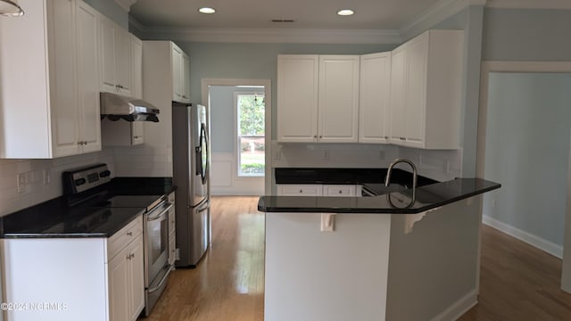 kitchen featuring light wood finished floors, wall chimney exhaust hood, appliances with stainless steel finishes, a peninsula, and crown molding